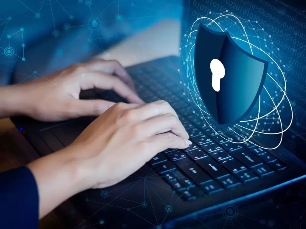 a person typing on a laptop with a sheild with a key hole which depict the protection of data