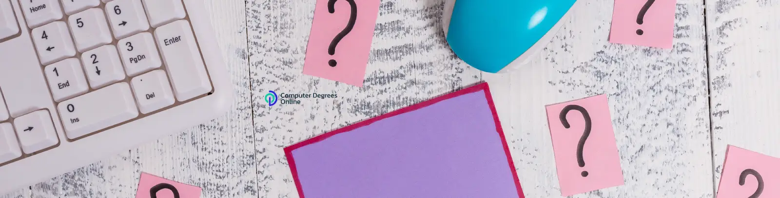 A white desk with a keyboard, a blue mouse, pencils, earphones, and pink question-mark sticky notes arranged around a blank purple note card.