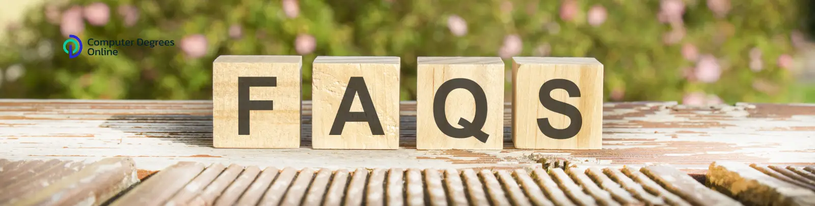 Wooden blocks arranged to spell 'FAQS' on a rustic surface with a blurred outdoor background.